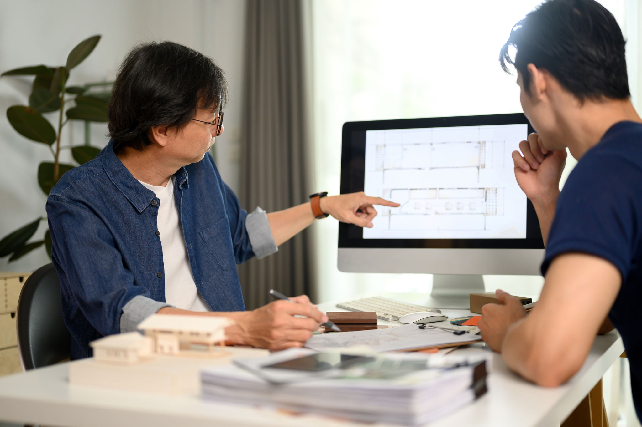 Professional architect man pointing on computer monitor discussing building plan design project with his client.